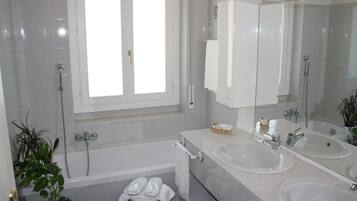 Ein modernes Badezimmer mit zwei Waschbecken, einer Badewanne und einem großen Spiegel.
