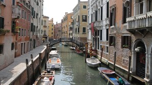 A narrow canal in Venice with boats docked along the sides and a bridge in the distance. - Hotel Palazzo Abadessa (Venice)