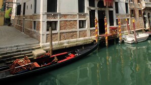 A historic building with a canal view, featuring a traditional Venetian window design and a red banner. - Hotel Palazzo Abadessa (Venice)