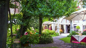 A courtyard with a stone pathway, a covered seating area, and lush greenery. - Hotel Palazzo Abadessa (Venice)