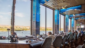 Un restaurante con vistas a un lago, amplias ventanas y una zona de bar.