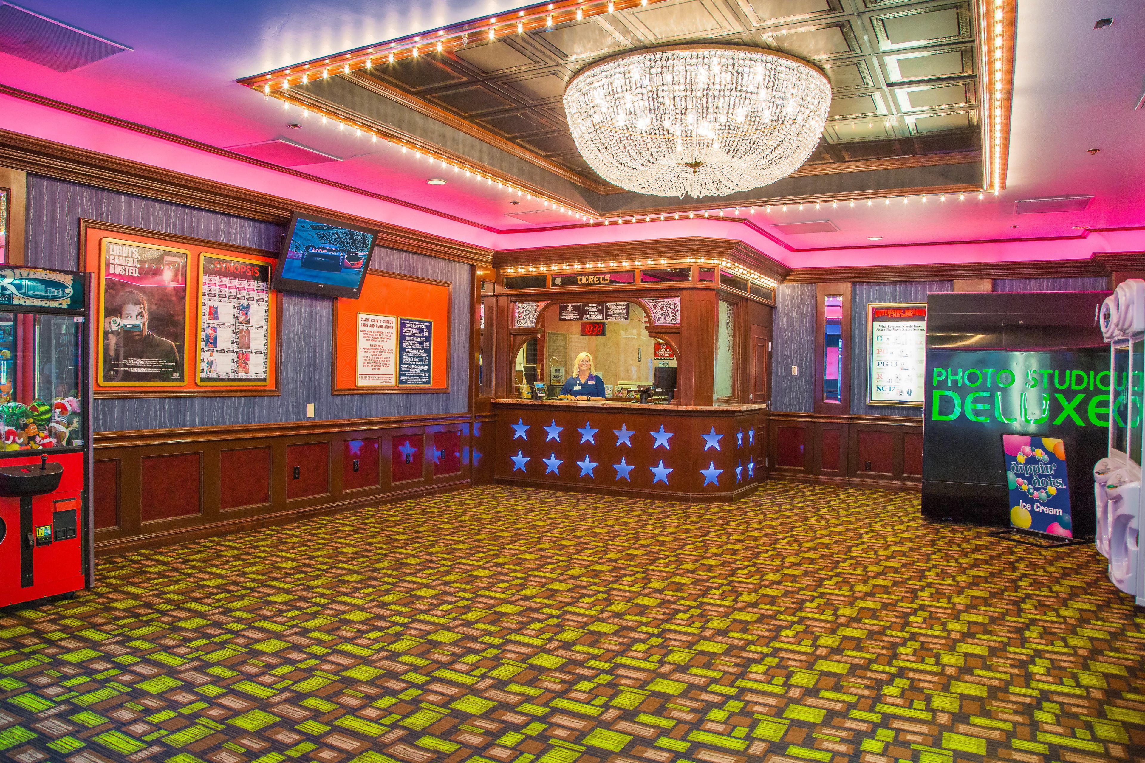 A lobby with a patterned floor, a chandelier, a ticket counter, and a photo studio.