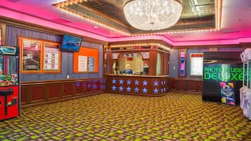 A lobby with a patterned floor, a chandelier, a ticket counter, and a photo studio.