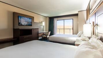 A hotel room with two beds, a desk, a TV, and a window with a view.