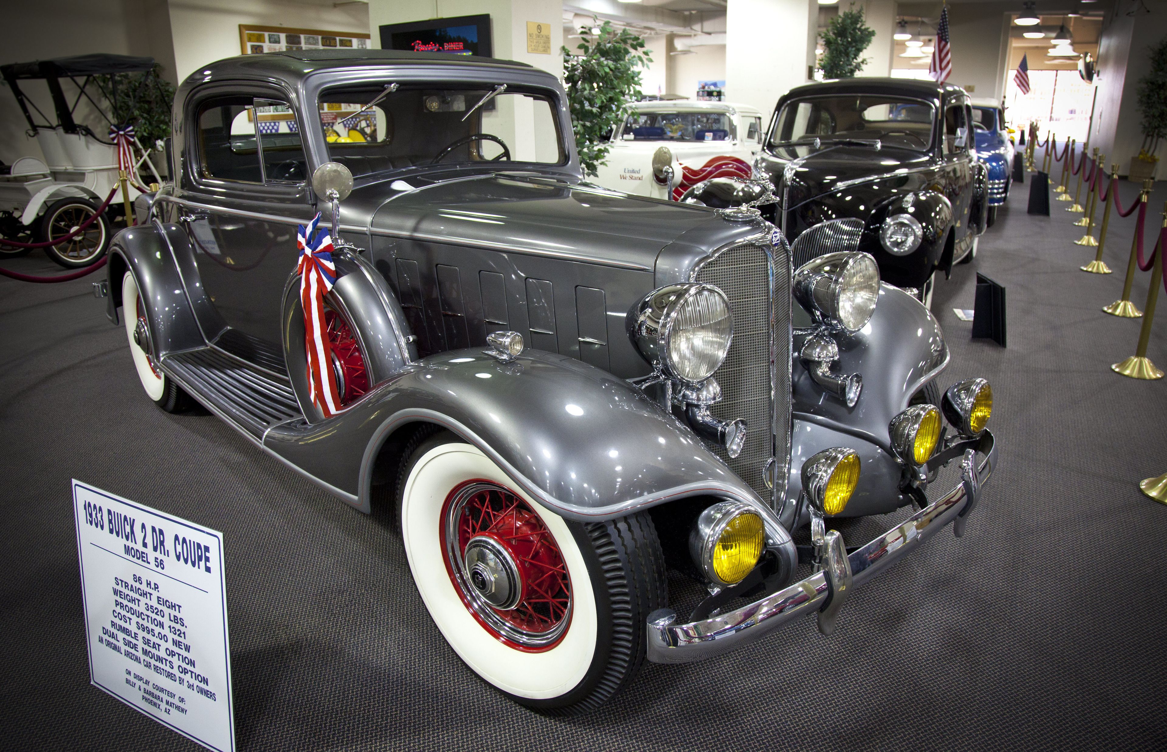 Une exposition de voitures anciennes, avec une affiche décrivant le modèle 1933 Buick 2 DR. COUPE, modèle 56.