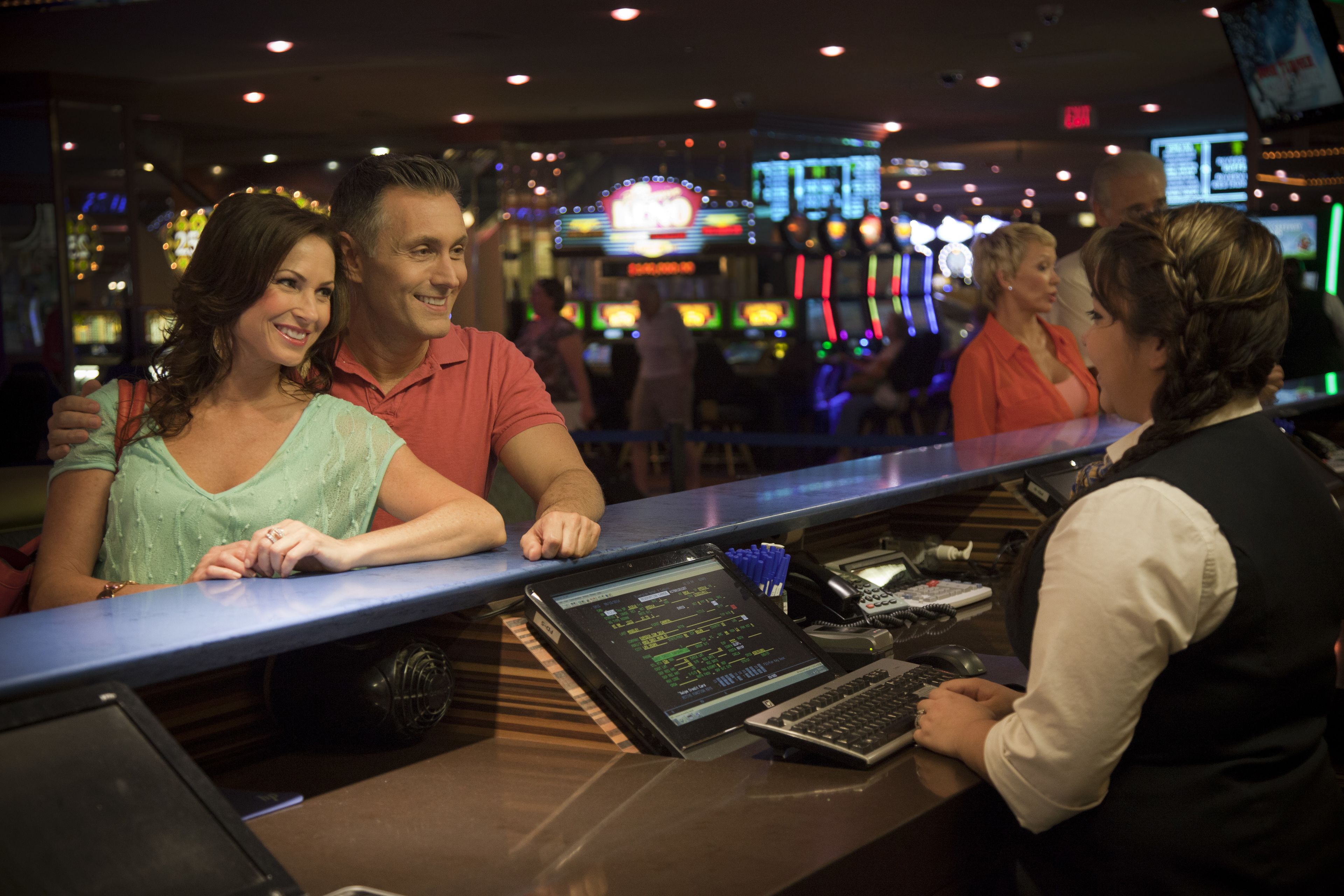 A bar area with a counter, slot machines, and a digital screen in the background.