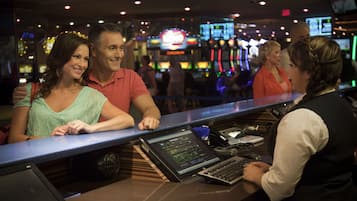 A bar area with a counter, slot machines, and a digital screen in the background.
