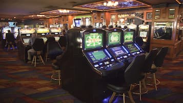 A casino with multiple slot machines and bar stools.