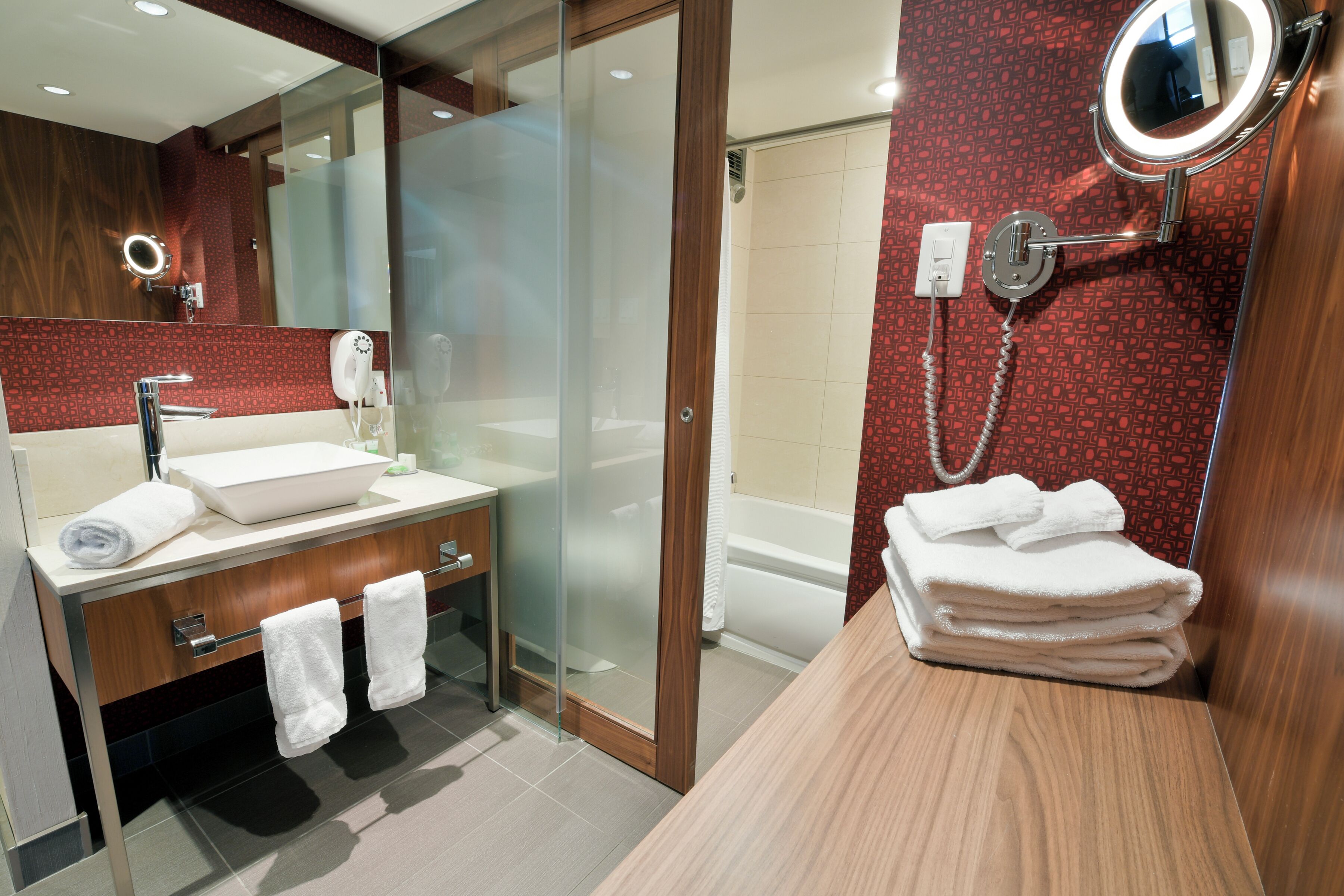 Une salle de bain moderne avec une douche à parois de verre, un meuble-lavabo avec un miroir et un porte-serviettes.