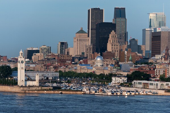 Un horizonte urbano con edificios históricos y modernos, una destacada torre del reloj y un puerto deportivo con barcos.