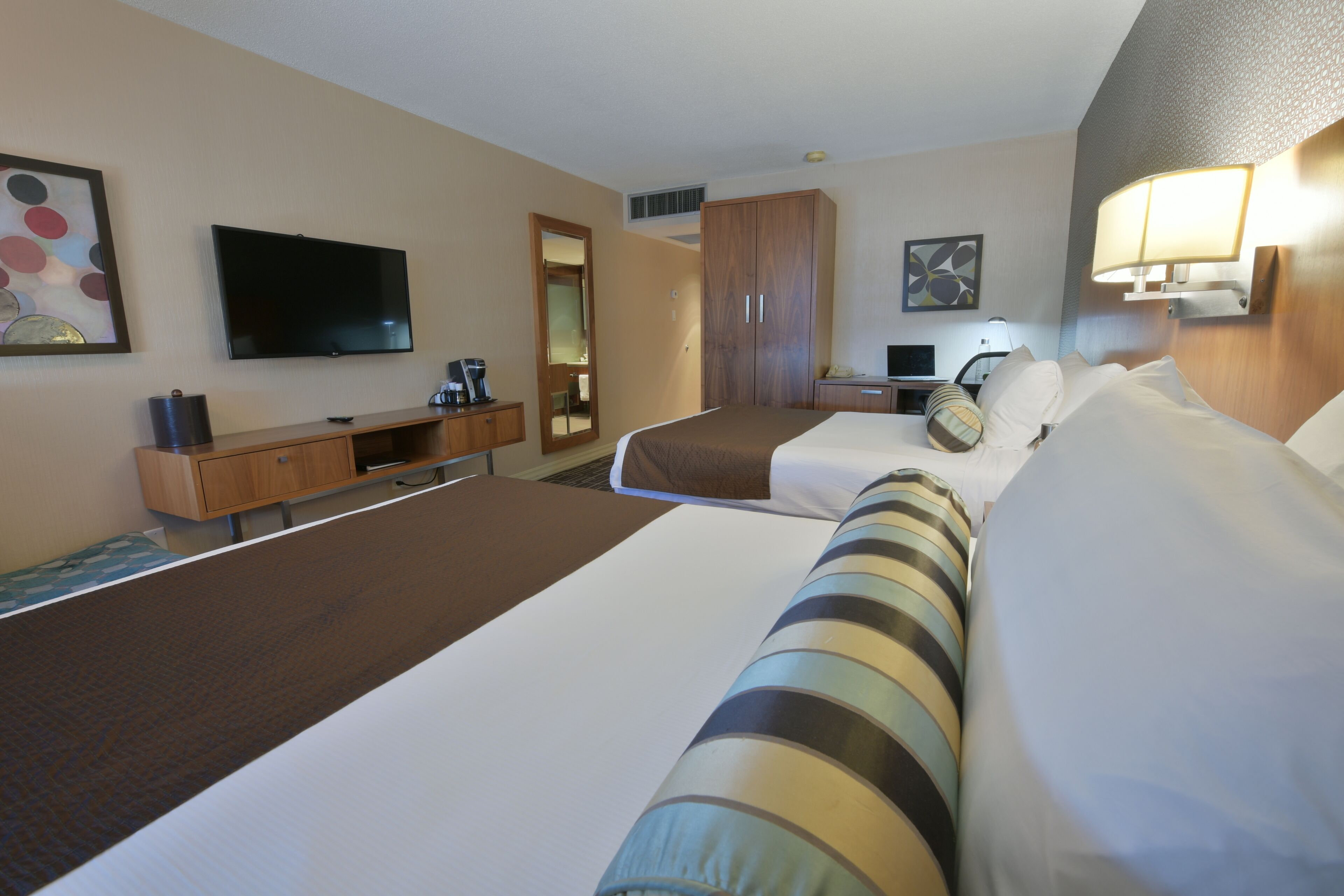 Una habitación de hotel con dos camas, televisión, escritorio y armario.
