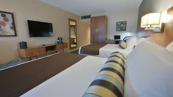 Una habitación de hotel con dos camas, televisión, escritorio y armario.