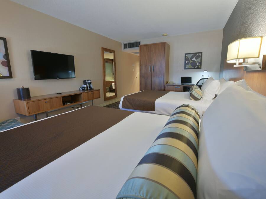 Una habitación de hotel con dos camas, televisión, escritorio y armario.