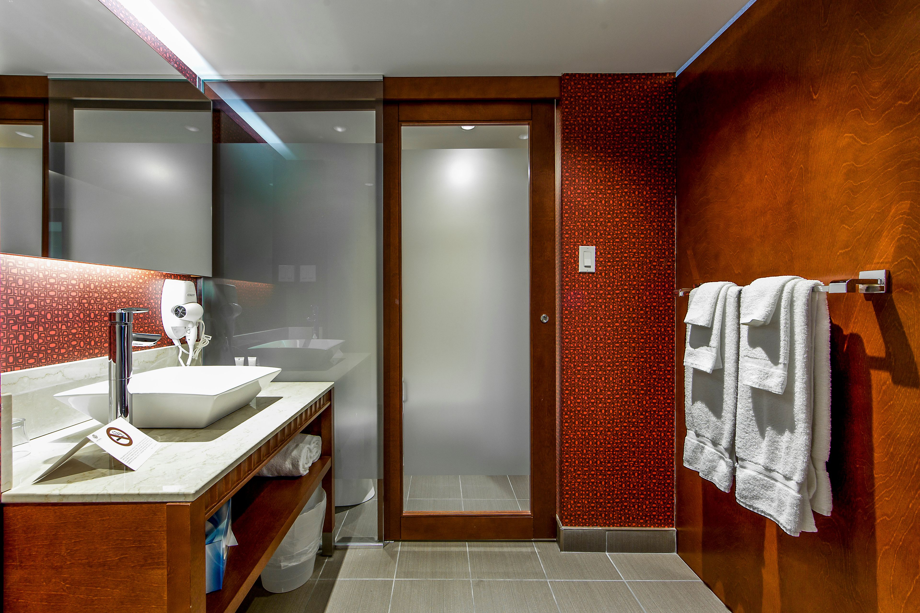 A modern bathroom with a large mirror, a white sink, and a shower area.