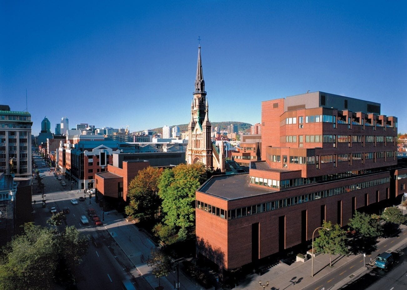 A cityscape with a prominent church steeple, a modern red building, and a mix of older and newer architecture.