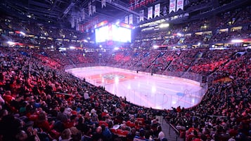 En stor indendørs arena med flere niveauer af siddepladser, en central isbane og bannere hængende i loftet.