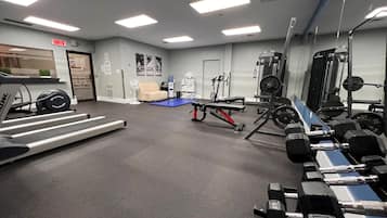Una palestra con tapis roulant, panche per pesi e diverse attrezzature per l'allenamento.