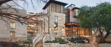 A modern building with a stone facade, a stone staircase, and a small water feature.
