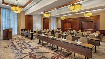 A conference room with long tables, chairs, and a podium.