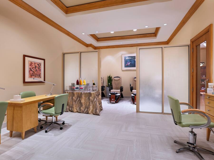 A conference room with a wooden desk, chairs, a table with refreshments, and a view through a partition.