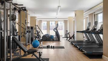 A gym with exercise equipment, treadmills, and a large window.