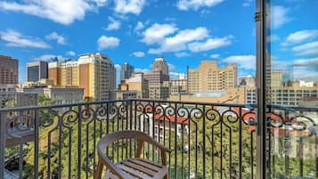 A balcony with a view of a cityscape, including various buildings and a clear sky.
