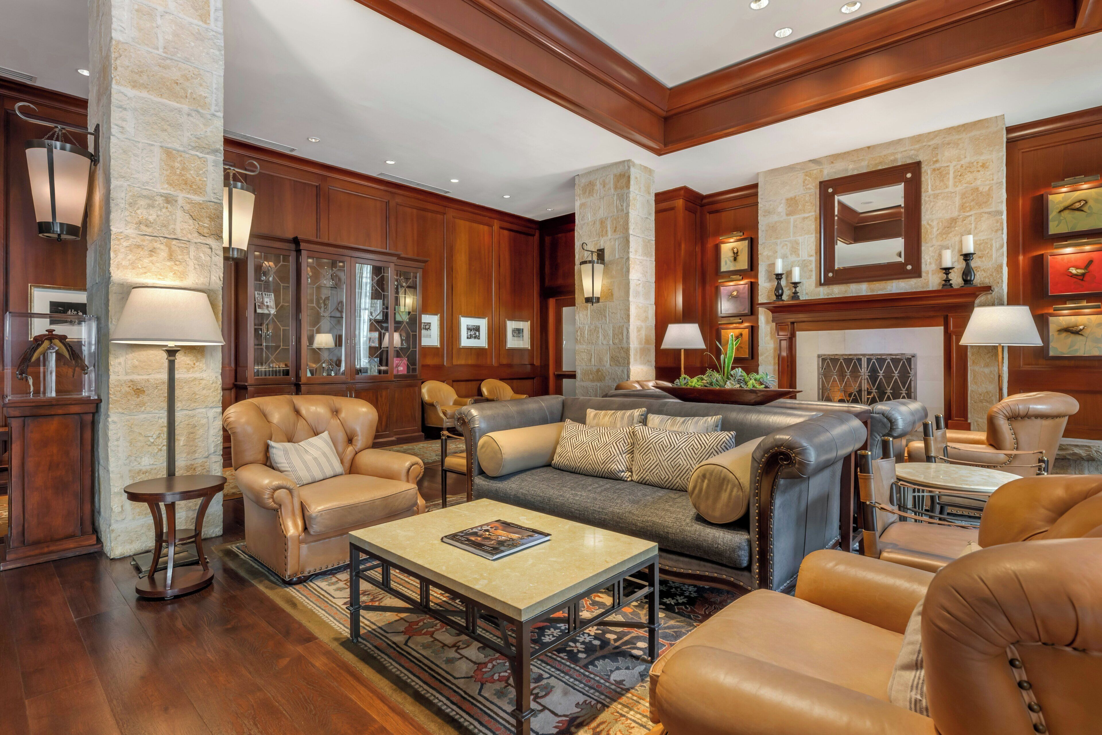 A spacious living room with leather sofas, a coffee table, and a fireplace.