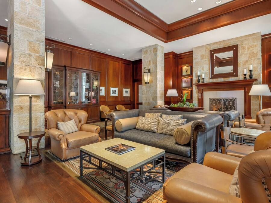 A spacious living room with leather sofas, a coffee table, and a fireplace.