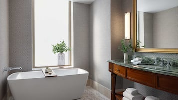 A modern bathroom with a freestanding bathtub, a large mirror, and a window with a view.