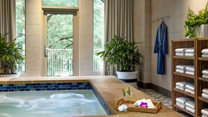 Zona de spa con jacuzzi, plantas en macetas y un perchero.