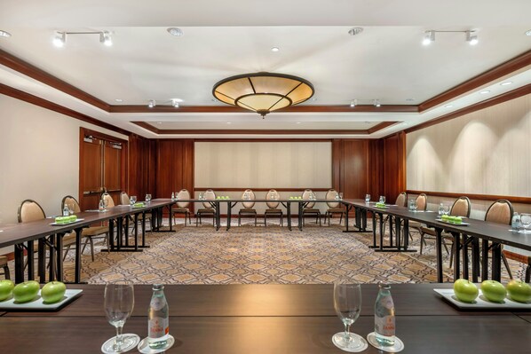Un salón de conferencias con una larga mesa, sillas y una araña.