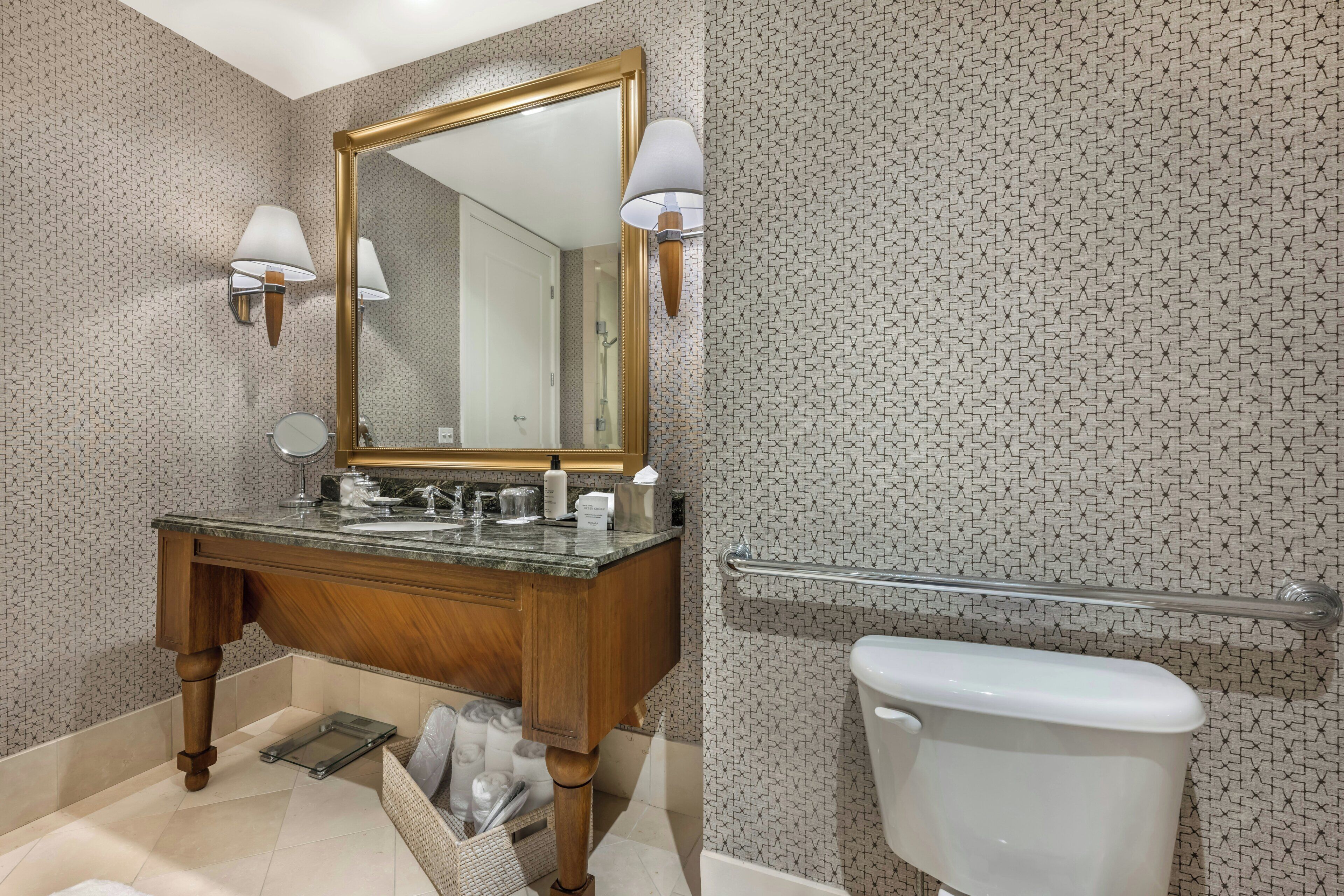 Une salle de bain équipée d’un meuble-lavabo, d’un miroir, d’un porte-serviettes et de toilettes.