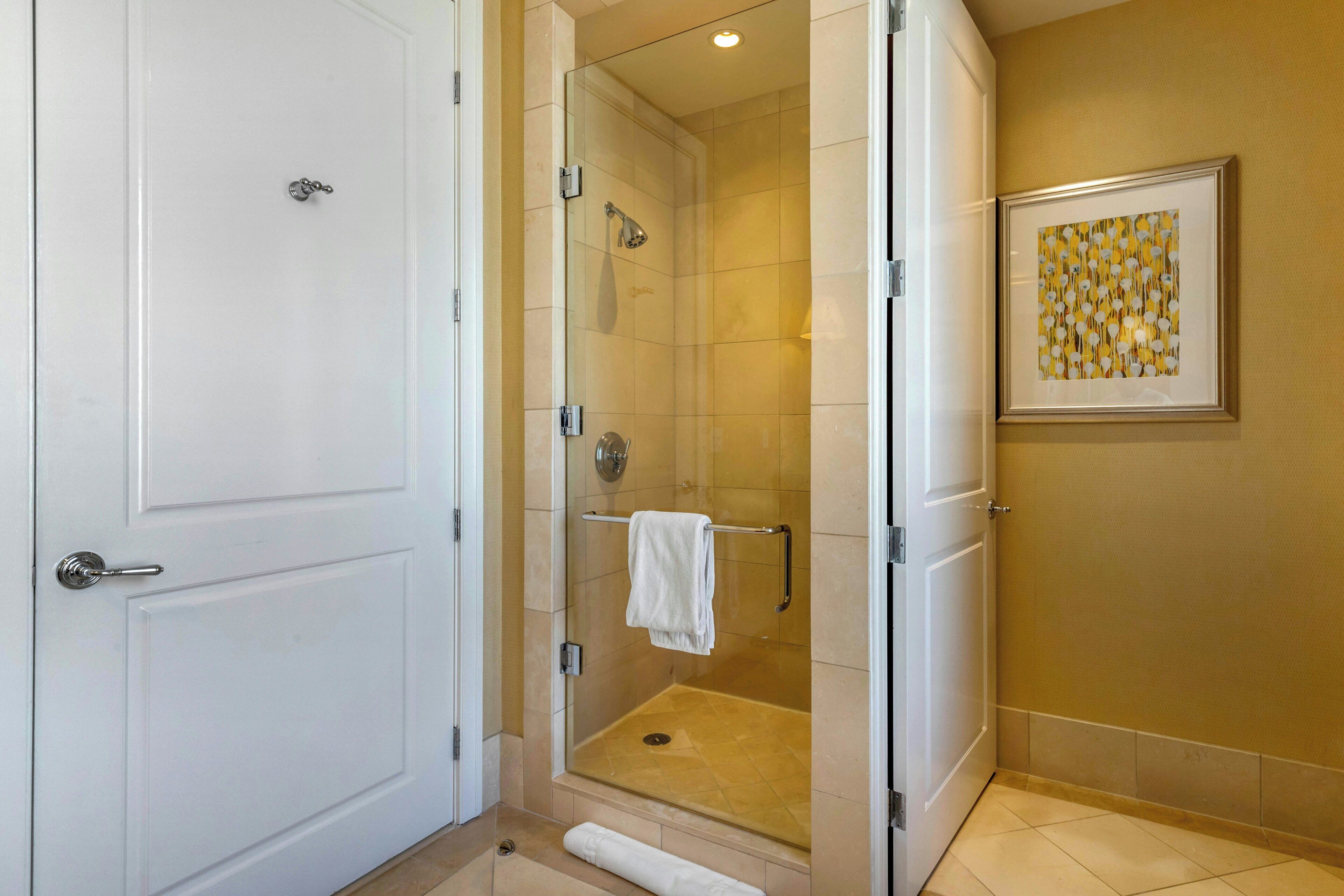 A walk-in shower with a glass door, a towel rack, and a framed picture on the wall.