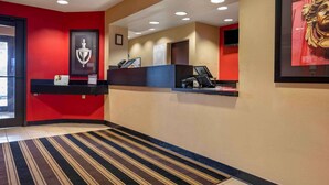 A reception area with a red wall, a black reception desk, and a framed artwork above it.
