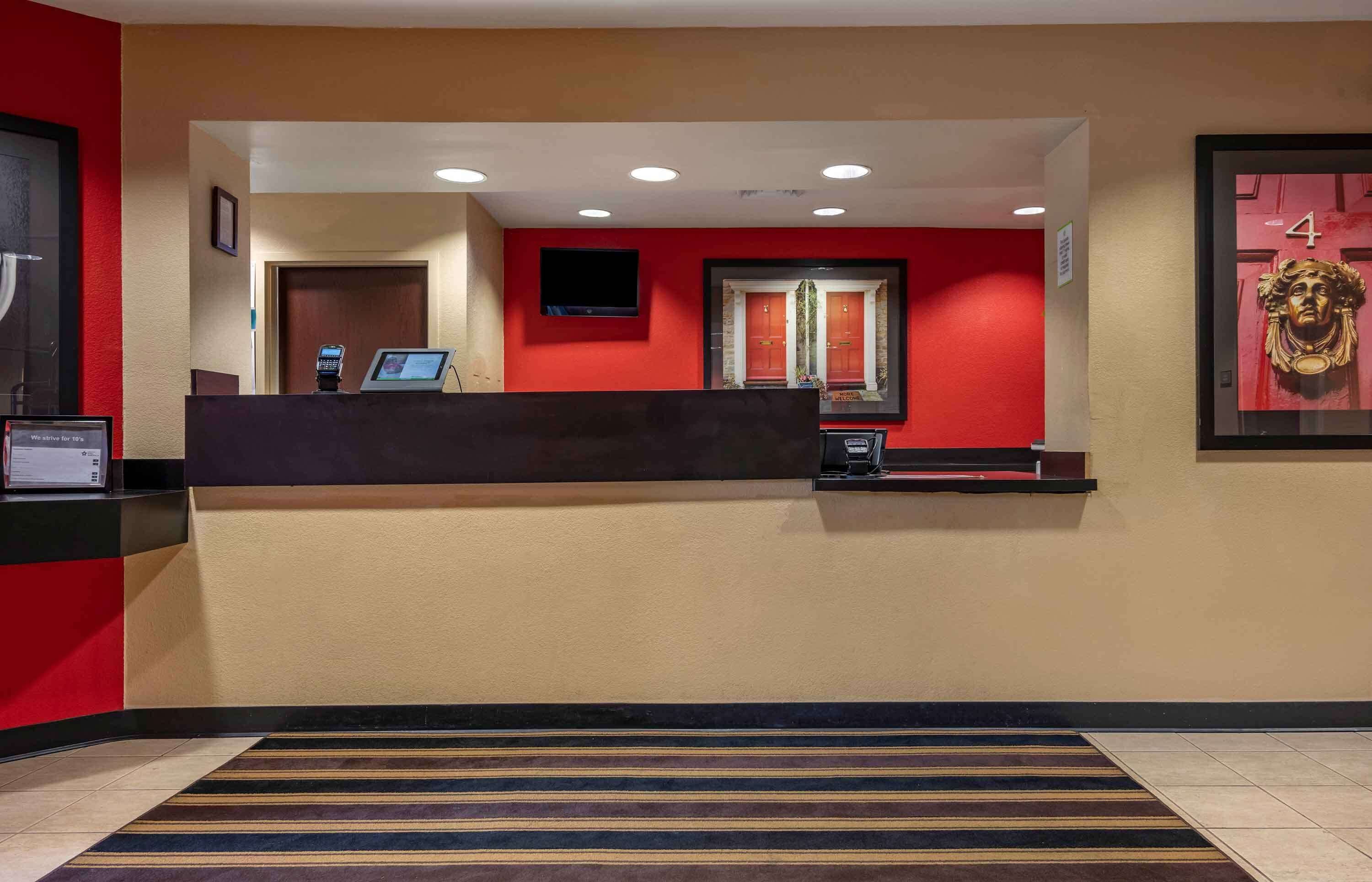 A reception area with a counter, a digital screen, and a framed picture on the wall.
