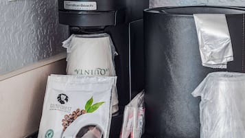 Une machine à café, une dosette de café et un sac de grains de café sur un comptoir.