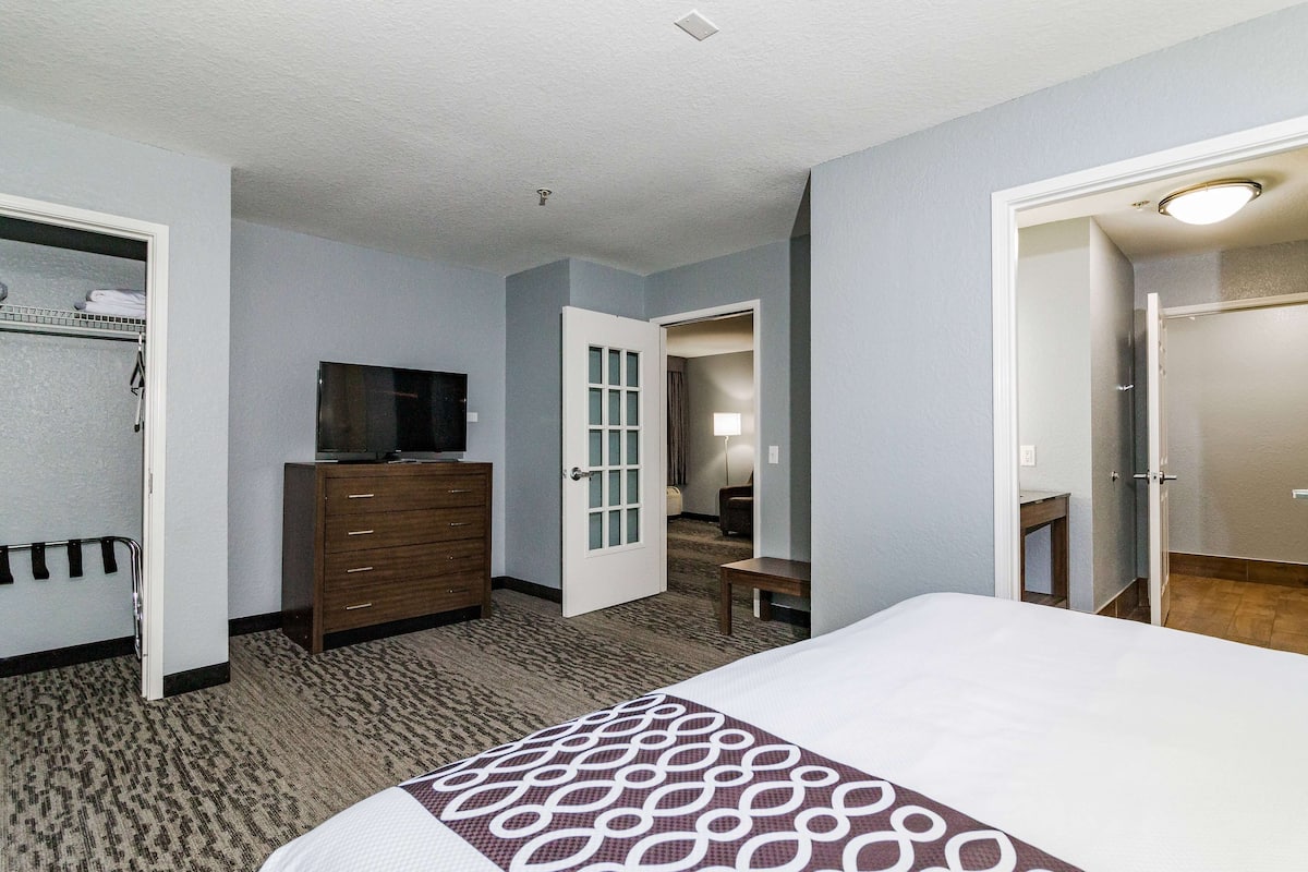 A hotel room with a bed, dresser, television, and a door leading to a bathroom.