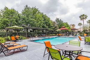 A poolside area with lounge chairs, a pool, and a pergola.