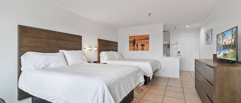 Una habitación de hotel con dos camas, un cabecero de madera, un escritorio pequeño, un aparador y un cuadro en la pared.