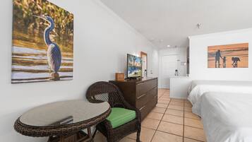 Una camera d'hotel con un letto, un tavolo da pranzo, una sedia in vimini, un comò e decorazioni alle pareti.