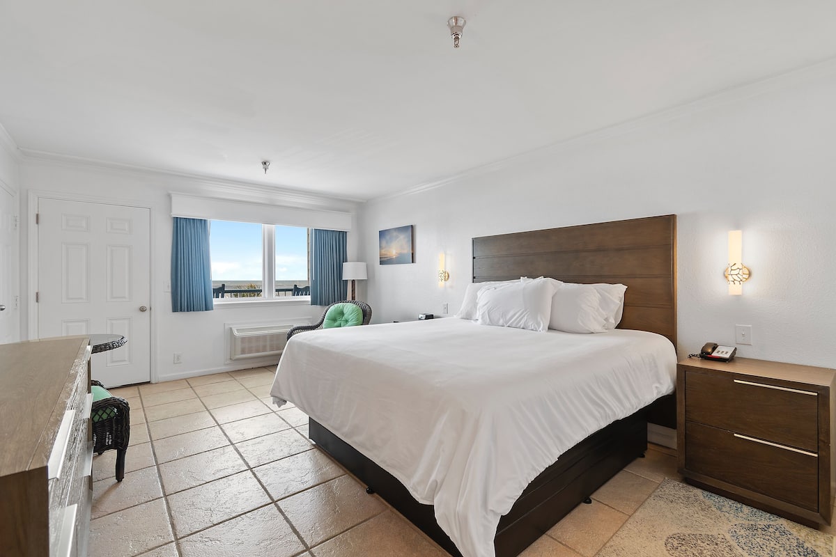 Une chambre d’hôtel avec un grand lit, un bureau, une chaise et une vue sur l’extérieur.