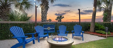 A patio area with Adirondack chairs, a fire pit, and a sign for Ocean Isle Inn.
