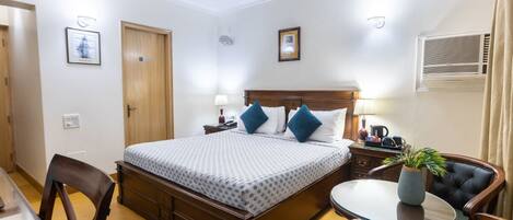 Une chambre d’hôtel comprenant un lit, des tables de chevet, un bureau, une chaise et un ventilateur de plafond.
