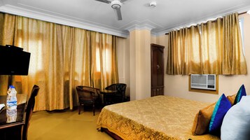 Una camera d'albergo con un letto, una scrivania con televisore, una sedia e un armadio.