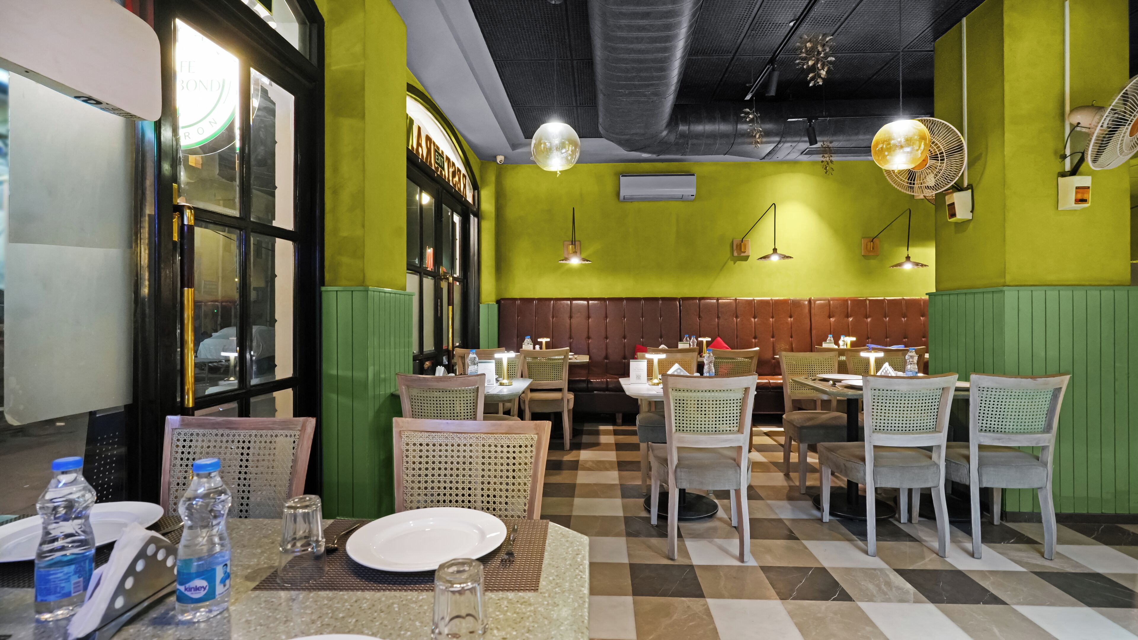 A restaurant interior with green walls, checkered flooring, and a variety of seating arrangements including booths and tables.