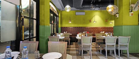 A restaurant interior with green walls, checkered flooring, and a variety of seating arrangements including booths and tables.