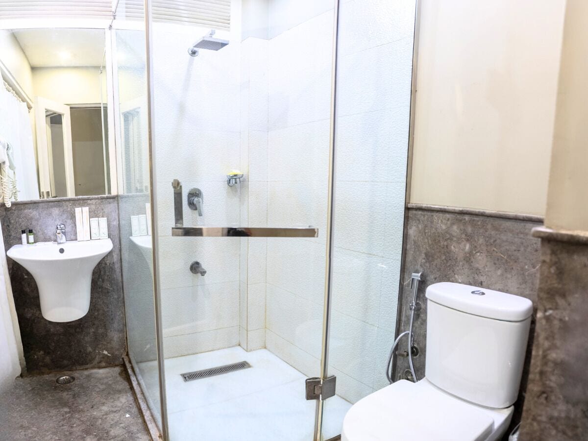Een badkamer met een douchecabine van glas, een wastafel en een toilet.