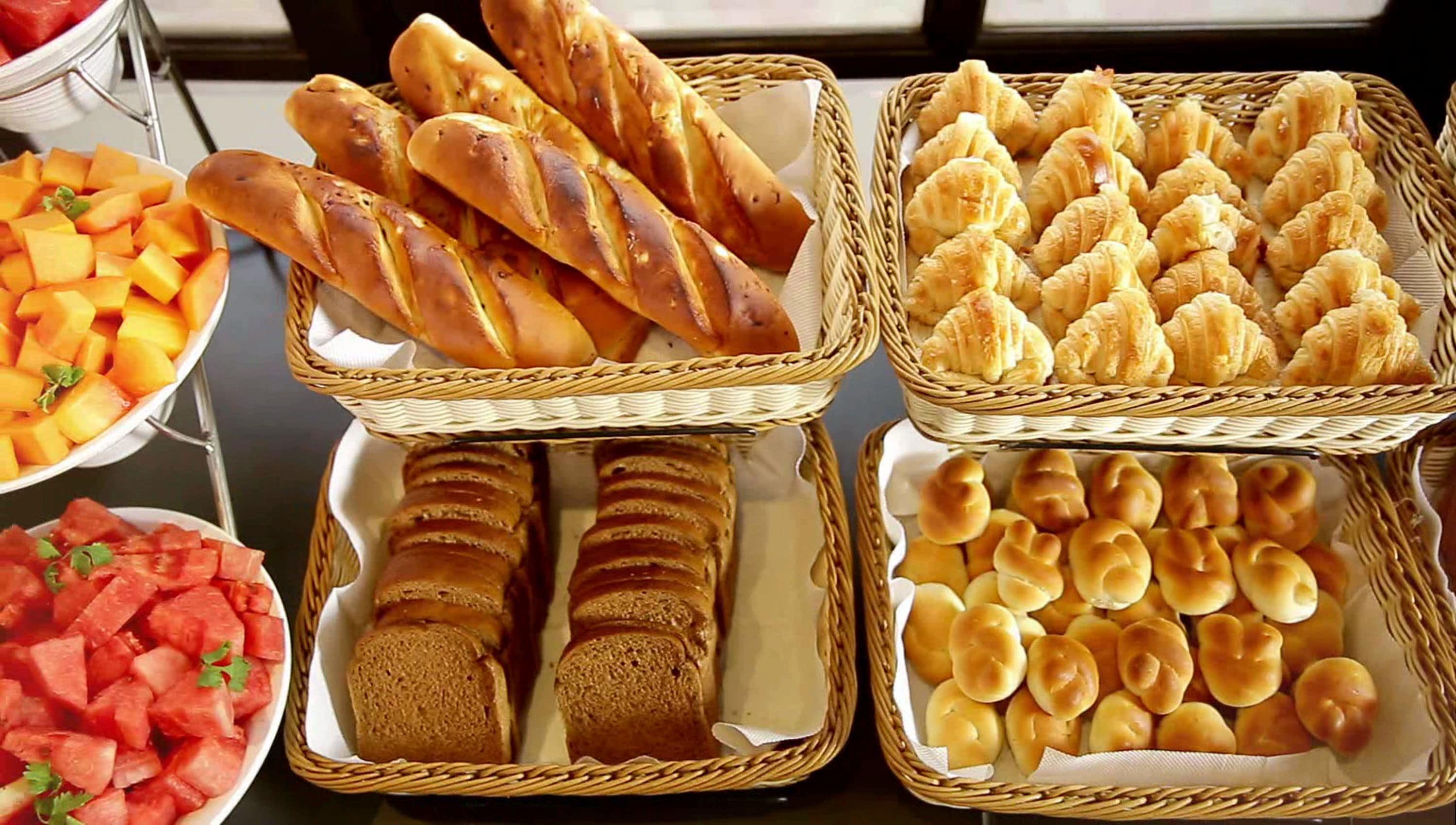 A buffet table with various bread and fruit options.