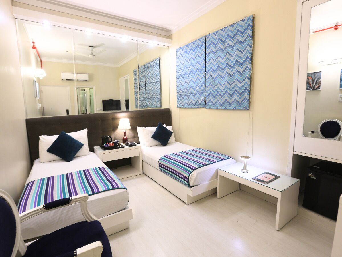 Habitación de hotel con dos camas, un escritorio, una silla, un espejo y una pared con diseño en zigzag.