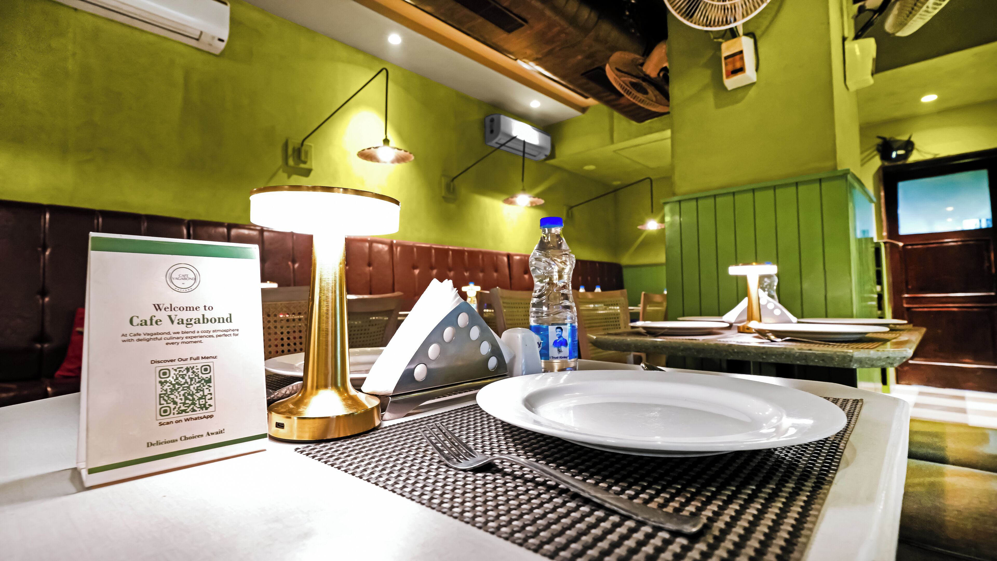 A restaurant setting with a table set for two, including a menu, a bottle of water, and a placemat.